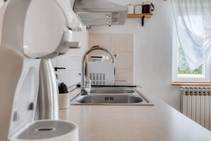 A modern kitchen with a stainless steel sink, a built-in range hood, and a window with sheer curtains.