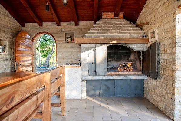A stone fireplace with a fire, wooden bench, and a rustic stone wall.