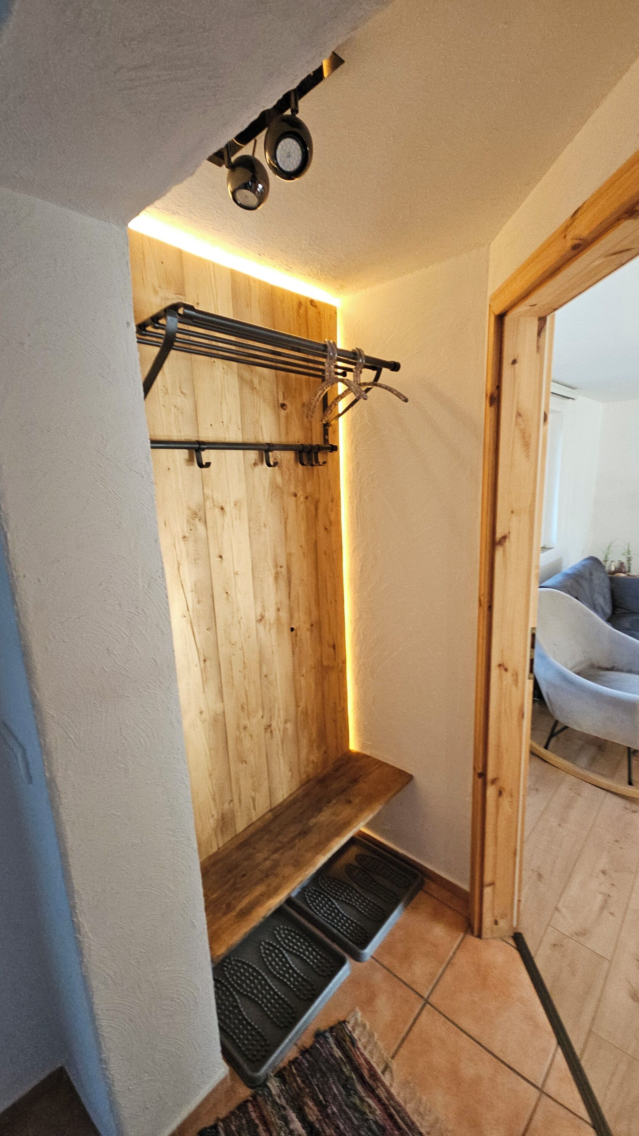 Un interior de madera con un banco incorporado, un estante metálico y un pequeño escalón que lleva a una puerta.