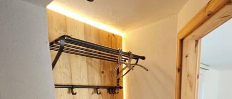Un interior de madera con un banco incorporado, un estante metálico y un pequeño escalón que lleva a una puerta.