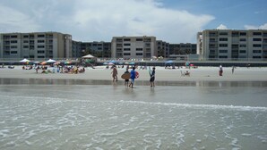 A beach with a building in the background. - 1 Bdrm..2026 Year-round time slots ..great View & Reviews...on the no drive sand (New Smyrna Beach)