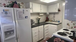 A kitchen with white cabinets, a stove, a sink, and a coffee maker.
