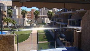 Ein Balkon mit Blick auf einen Pool, Palmen und moderne Gebäude.