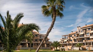 Ein Resort mit Swimmingpool, Palmen und mehrstöckigen Gebäuden mit Balkonen.