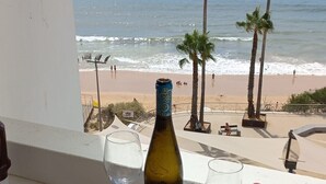 Ein Tisch mit Speisen und Getränken mit Blick auf einen Strand, an dem Palmen und das Meer zu sehen sind.