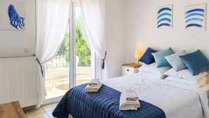 A bedroom with a bed, a nightstand, a lamp, and a view of the outdoors. - Luxurious and family friendly villa with large private pool 5 mins from Skiathos (Skiathos)