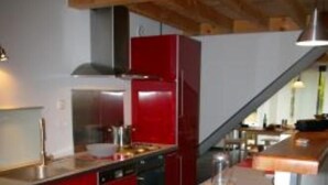 Una cocina moderna con armarios rojos, una isla central y una campana extractora de acero inoxidable.