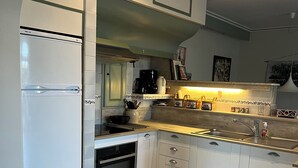 Een moderne keuken met witte kastjes, een inbouwoven, een spoelbak en een koffiezetapparaat.