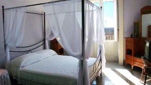 Une chambre à coucher avec un lit à baldaquin, une commode en bois et un téléviseur.
