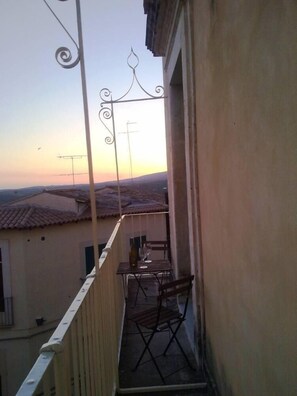 Ein Balkon mit Tisch und Stühlen, der auf ein Wohngebiet mit Ziegeldächern blickt.