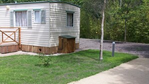 Un’abitazione mobile con un piccolo portico, un ponte in legno e un prato.