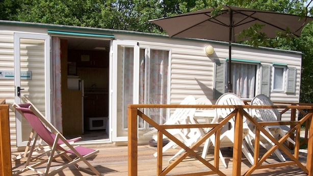 Una casa mobile con veranda, una sedia da patio e un tavolo con sedie.