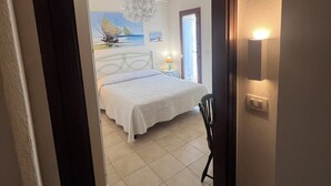 Een slaapkamer met een bed, een stoel, een lamp en een schilderij aan de muur.