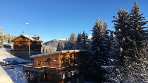 A wooden chalet with a balcony, surrounded by snow-covered trees and mountains in the background. - COURCHEVEL 1850 RESIDENCE CHALET STYLE - BEAUTIFUL VIEW ON MASSIF DE LA VANOISE (Courchevel)