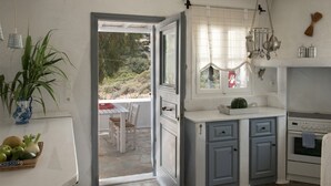 A kitchen with a stone countertop, a window with curtains, and a hanging light fixture.