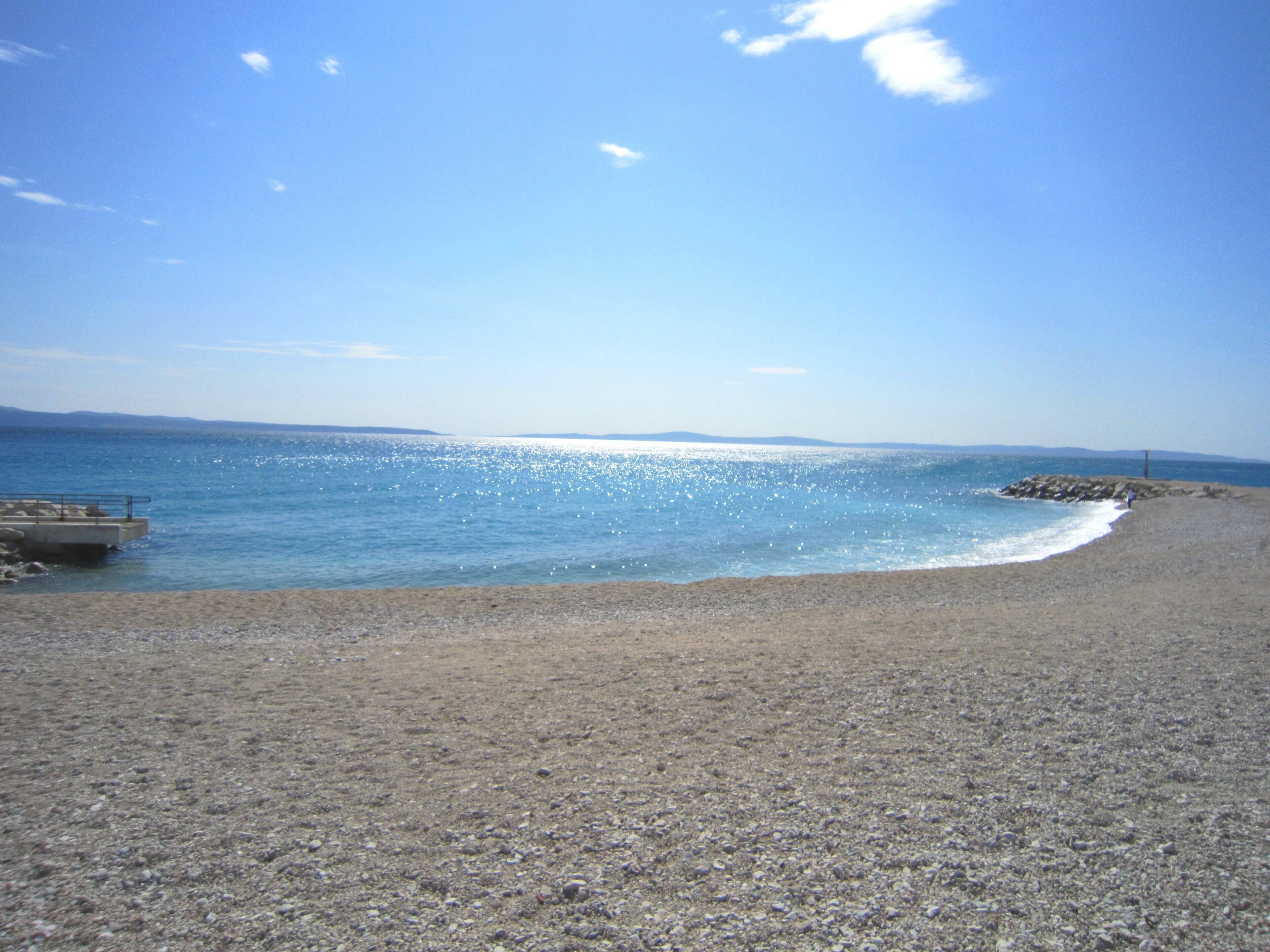 A beach with a rocky shoreline and a clear blue sky.