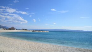 A beach with clear blue water, a rocky breakwater, and a few buildings in the background. - Romantic Apartment Johnny I, hot tub in garden, Studio in Split center, Croatia  (Split)