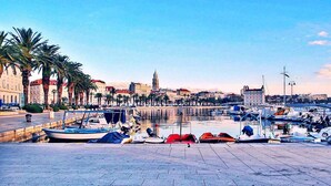 A marina with boats docked, a waterfront promenade lined with palm trees, and historic buildings in the background. - Romantic Apartment Johnny I, hot tub in garden, Studio in Split center, Croatia  (Split)