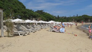 A beach with rows of sun loungers and umbrellas, a sandy shore, and a backdrop of trees. - NEW VILLA LES CORALINES, WITH SEA VIEW AND SHARED POOL (Roquebrune-Sur-Argens)
