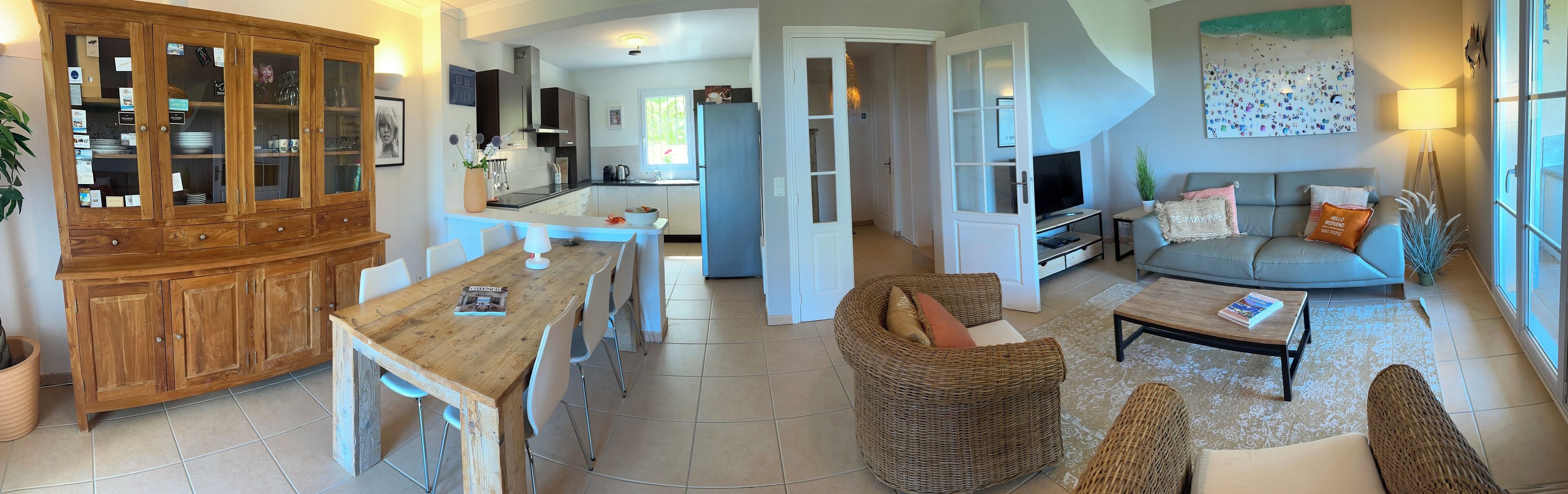 Amplia sala de estar con mesa de comedor, muebles de mimbre y televisor.