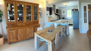 A spacious living area with a dining table, wicker furniture, and a television. - NEW VILLA LES CORALINES, WITH SEA VIEW AND SHARED POOL (Roquebrune-Sur-Argens)
