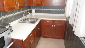 Una cocina con armarios de madera, un lavaplatos de acero inoxidable y un microondas.