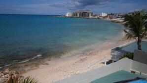 Una propiedad frente a la playa con piscina, playa de arena y vista al océano.