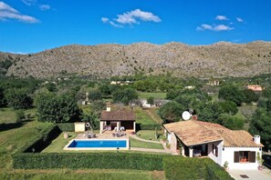 Uma villa com piscina, alpendre e vista para as colinas ao redor.