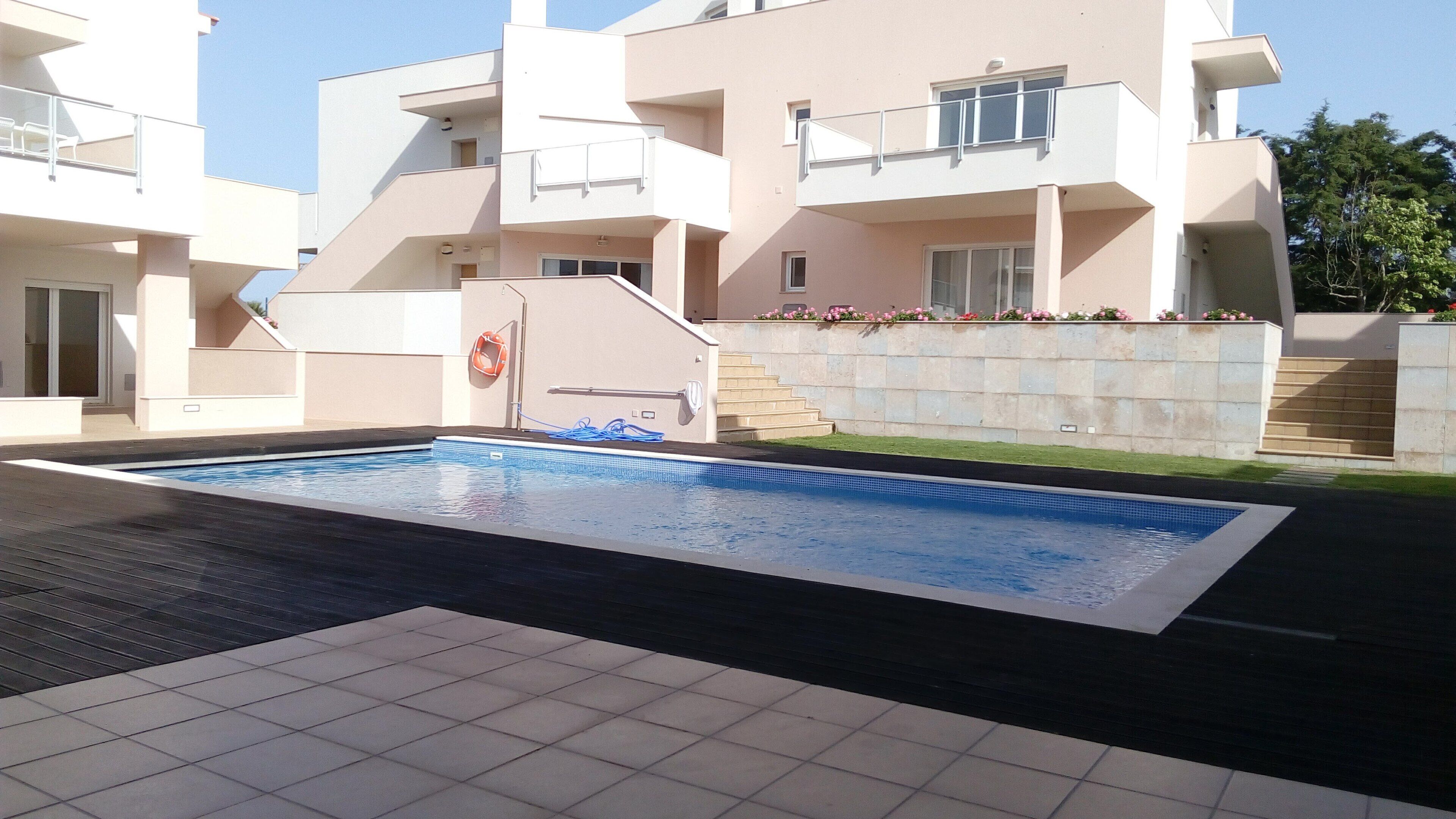 Un moderno complejo de apartamentos con piscina, balcones y una escalera que conduce a los pisos superiores.