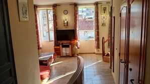 Una sala de estar con televisión, un reloj y una ventana con cortinas.