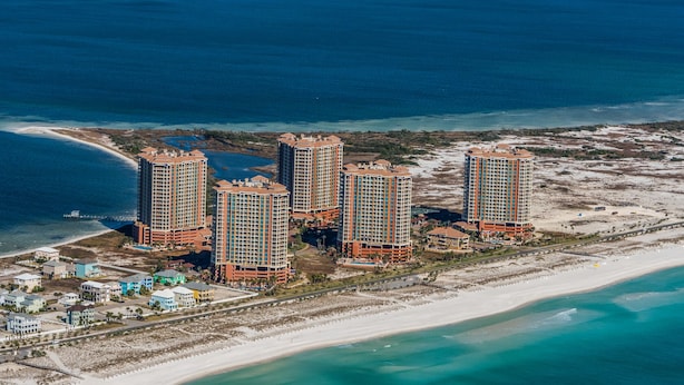 Un complejo hotelero de gran altura con varios edificios, una playa y un puerto deportivo.