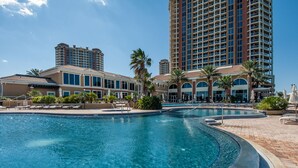 Un hotel con un amplio espacio de piscina, varias construcciones y palmeras.