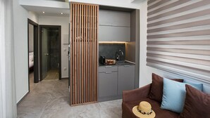 Un espacio de sala moderno con un sofá, una cocina y una puerta corrediza que separa ambas áreas.