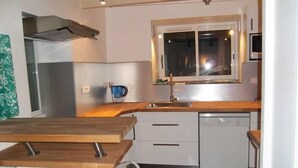 A modern kitchen with a wooden countertop, white cabinetry, a built-in oven, and a window above the sink. - Large capacity houses in the village (Les Portes-En-Ré)