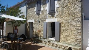 A stone building with a patio area, outdoor seating, and a table with chairs. - Large capacity houses in the village (Les Portes-En-Ré)