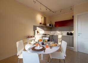 Una cucina moderna con elettrodomestici bianchi, un tavolo da pranzo per due persone e una parete decorata in rosso.