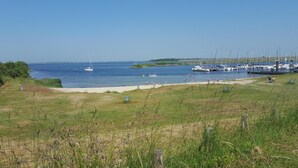 A marina with boats docked, a sandy beach, and grassy areas. - Gezellig vakantiehuisje vlakbijhet Grevelingenmeer, huisdieren toegestaan. (Holland)