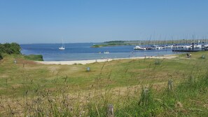 Un puerto deportivo con barcos amarrados, una playa de arena y zonas verdes.
