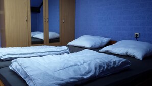 Une chambre avec un lit, des oreillers blancs et une armoire avec des miroirs.