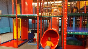 Un espace de jeux avec un toboggan rouge et des structures d’escalade en forme de réseau.