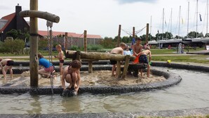 Un espace de jeux aquatiques doté d’une structure en bois et bordé de pierres.