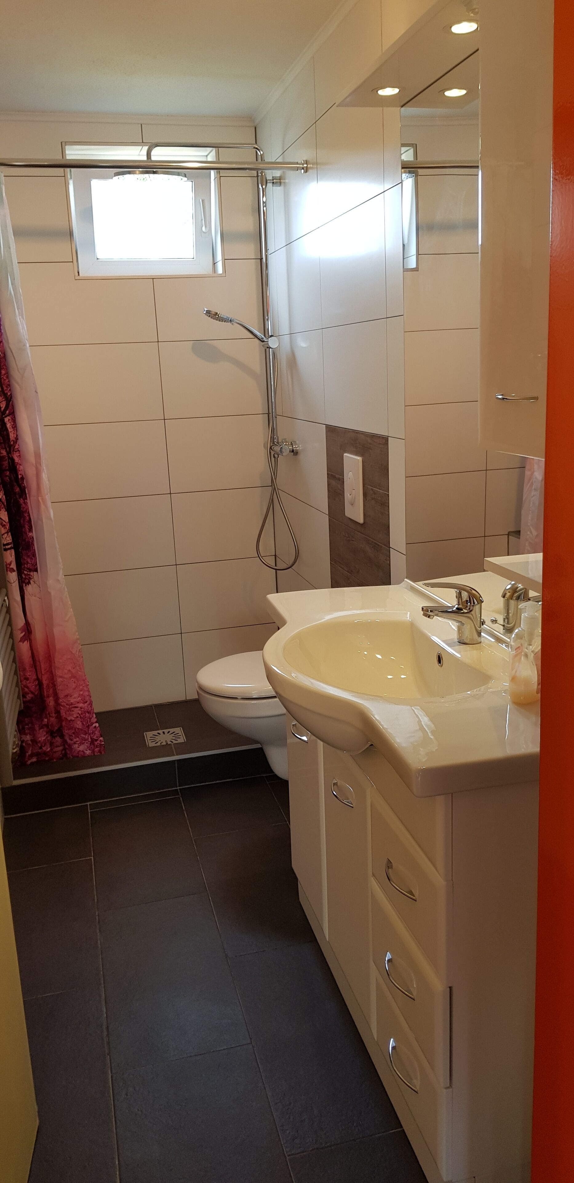 A modern bathroom with a shower, toilet, and sink.