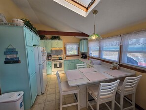 Una cucina compatta con zona pranzo, un lucernario e vista all'esterno attraverso le finestre.