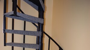 Escadaria em espiral com estrutura de metal preto e degraus carpetados.