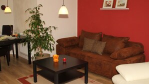 A living room with a brown sofa, a white sofa, a black coffee table, and a potted plant.