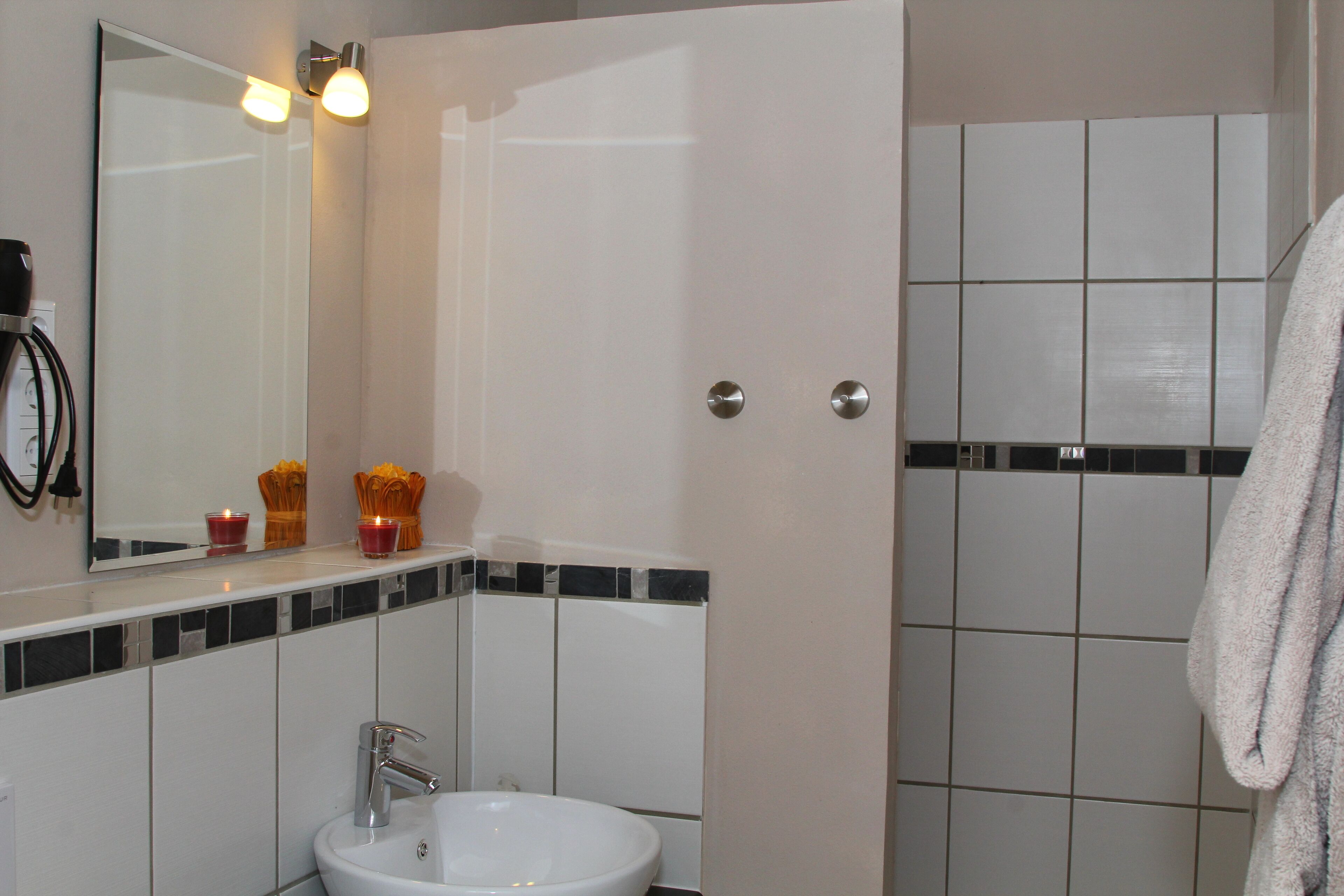 A bathroom with a sink, mirror, and tiled walls.