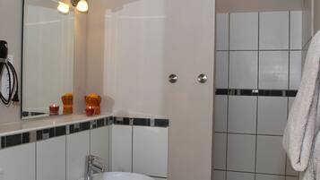A bathroom with a sink, mirror, and tiled walls.
