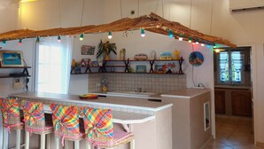 A kitchen with a central island, a dining area with chairs, and a ceiling with exposed beams.