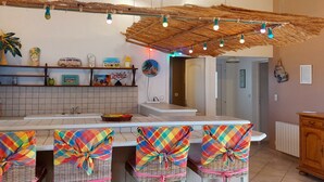 A kitchen with a central island, bar stools, a hanging light fixture, and a rustic ceiling.