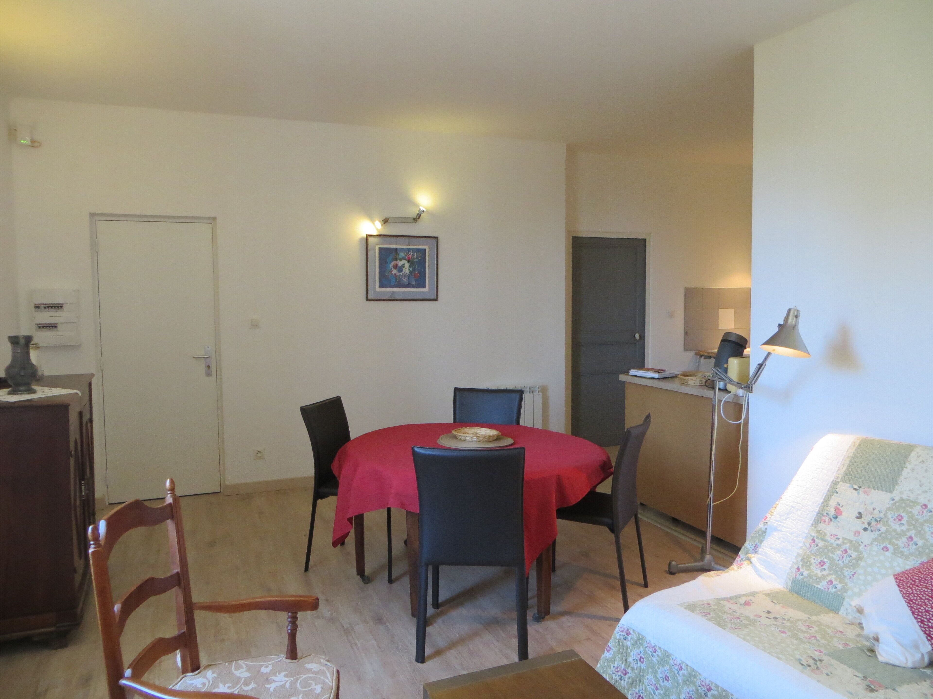 A compact room with a dining table, chairs, a sofa, and a lamp.